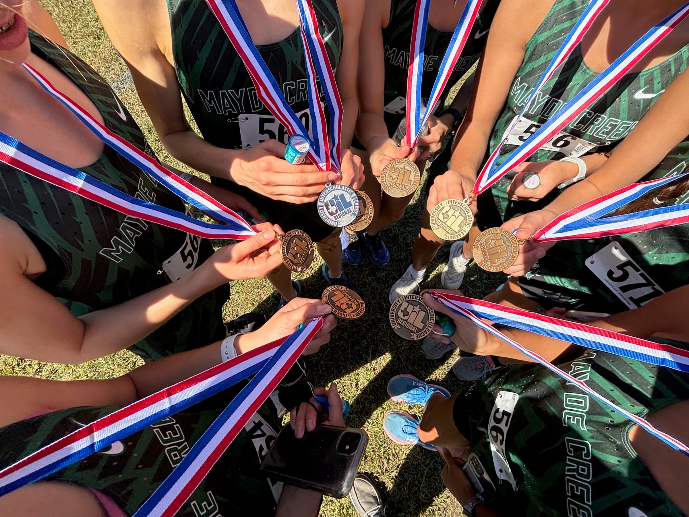 Team gathered in a circle holding State-qualifying medals